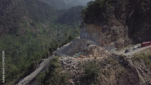 Aerial view of the excavator working on the serpentine road in Vietnam Dalat. Landslide. Vehicle trapped on traffic jam because of the rocks. 