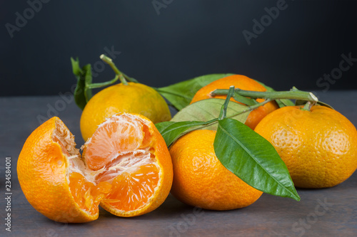 yellow sweet isolated peeled and whole mandarin clementine tangerine on wooden rustic vintage table with leaf. Tangerines background concept
