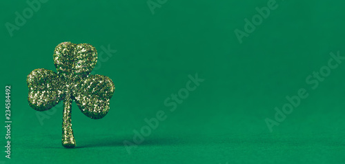 Glitter shamrock on green paper background. St Patricks day symbol. Irish National holiday concept
