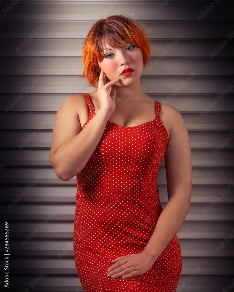 Redhead asian brazilian woman, spotlight effect, glamour shot on a grey  textured background with a red dress and lipstick makeup Stock-Foto | Adobe  Stock