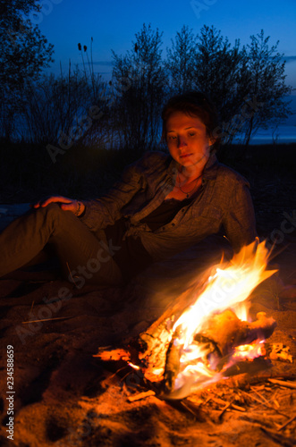 girl is heated sitting around a night fire