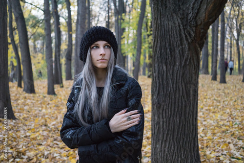 Portrait of young woman near tree in the autumn forest
