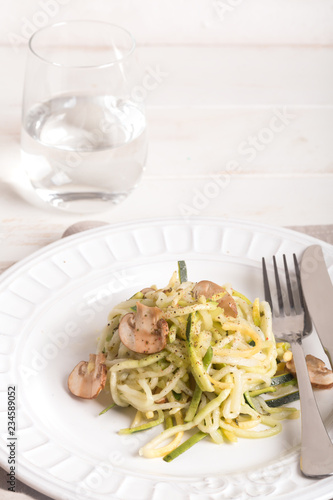 Plate of spaghetti prepared from zucchini and mushroom sauce on wooden table