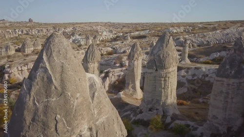 High angle advancing aerial drone view flying near through phallic fairy chimney or hoodoo formations and rocky landscape at daytime in Cappadocia, Turkey. 4k at 23.97fps