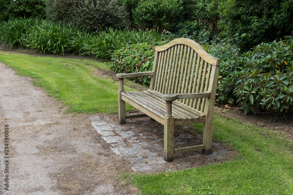 An empty wooden park bench in a public park. An empty wooden park bench in a public park.