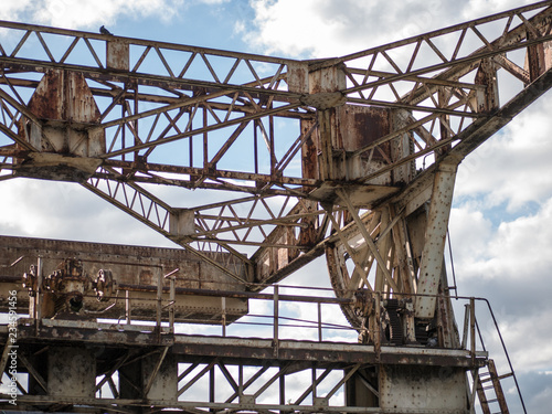 Old, rusty, dilapidated metal loading crane in the dock. 