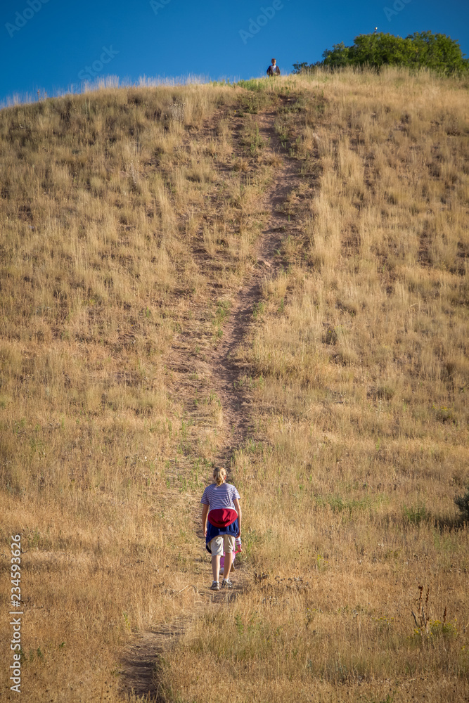 The back of a woman at bottom of hill walking up The back of a woman at bottom of hill walking up