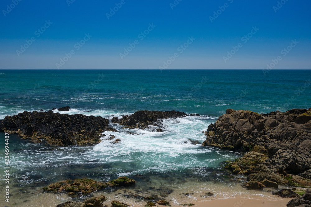 Beautiful rocky beach in Portugal, on sunny day with clear blue water and blue cloudless sky. Vila do Conde, Porto region.