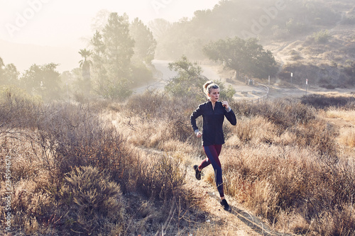 Beautiful Caucasian White Woman Runs on a Trail in the Morning Sunlight