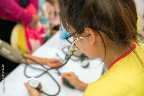 Volunteer nurse measuring blood pressure of poor Asian people outdoors closeup