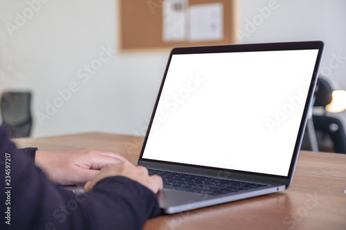 Mockup image of hands using and typing on laptop with blank white desktop screen while sitting in office