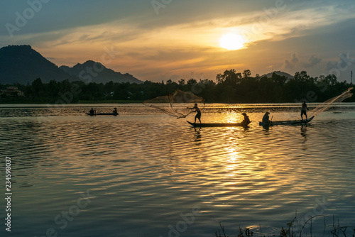Fisher men fishing on a fishing boat in river in Mekong Delta on floating water season at sunset