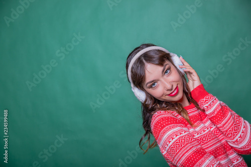 Winter Beauty Woman. Fashion Girl Concept. Skin and hair care in cold season. Beautiful woman with long hair wearing sweater and earmuffs. Holiday portrait of female wearing warm winter earmuff, copy