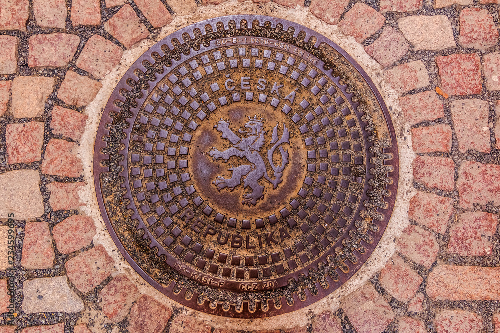 Ornate manhole cover with the Czech and Bohemian coat of arms with a lion in Prague, Czech Republic