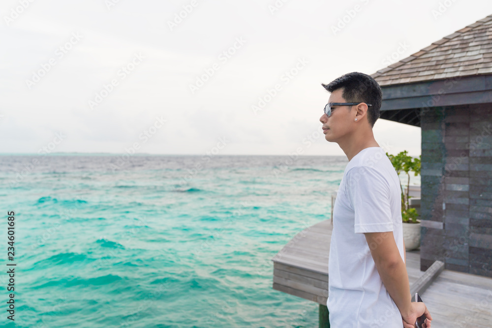 Asian smart man enjoyful traveling sea background.