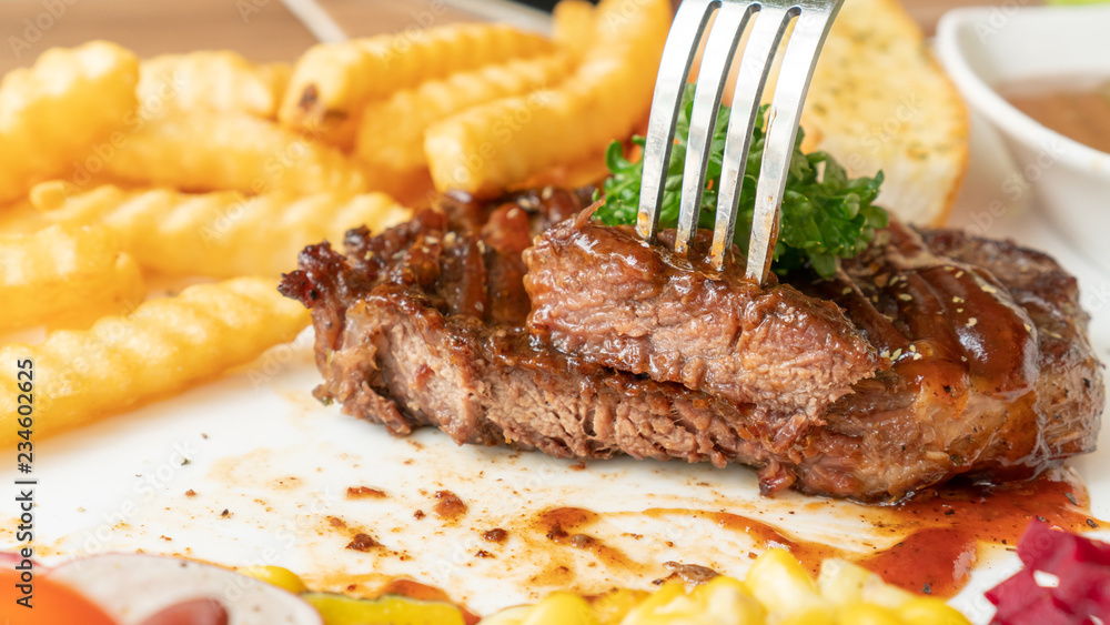 Beefsteak, French fries, and vegetable on a white plate. Beefsteak, French fries, and vegetable on a white plate.