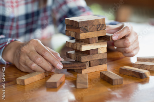 hand of businessman pulling out or placing wood block on the tower. plan and strategy in business.  Risk management, Challenge In Business Concept.
