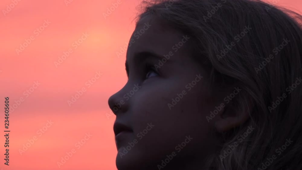 Kid looking up at the sky in nature. Little girl praying looking up at purple sky with hope, close-up. Kid looking up at the sky in nature. Little girl praying looking up at purple sky with hope, close-up.