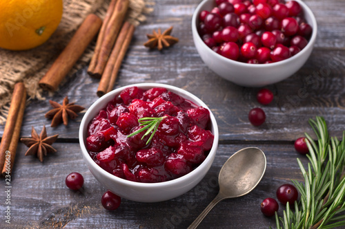 Homemade spicy cranberry sauce with fresh cranberries, cinnamon and star anise on a wooden background