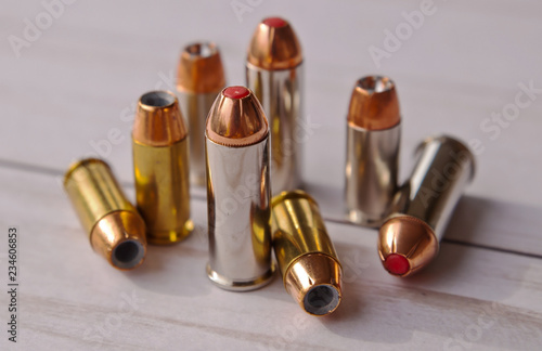 Eight bullets, five 40 caliber hollow points and and three 44 special red tipped ones on a white wooden background photo