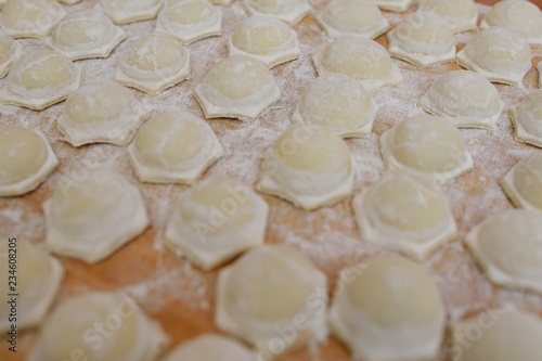 culinary background-raw dumplings or ravioli on wooden background
