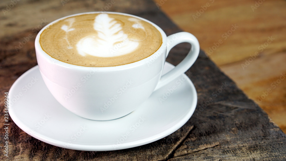 Cappuccino or latte art coffee. Free hand pouring some foam of milk on top. A white ceramic cup on the wood table with some coffee beans. The best food and drink in the world. Fresh energy everyday. Cappuccino or latte art coffee. Free hand pouring some foam of milk on top. A white ceramic cup on the wood table with some coffee beans. The best food and drink in the world. Fresh energy everyday.