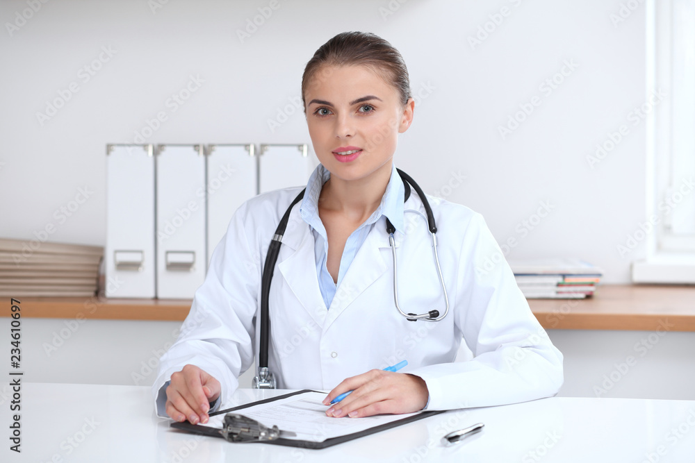 Doctor woman writing papers at the desk in hospital office. Medicine and over work concept Doctor woman writing papers at the desk in hospital office. Medicine and over work concept