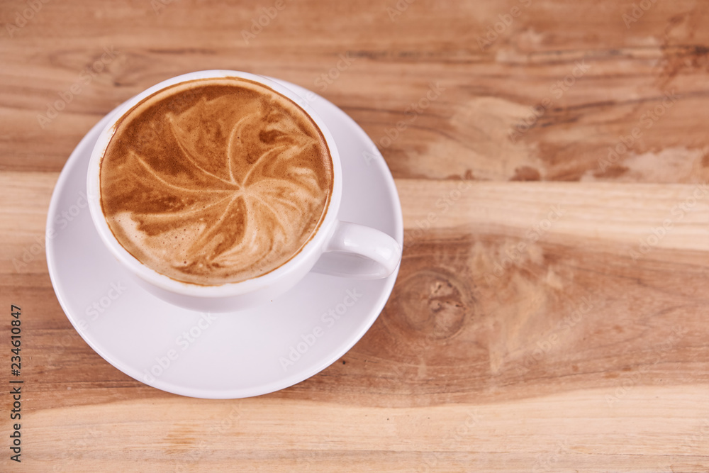 Hot cappuccino or latte art coffee. A cup of coffee on the wooden table with roasted beans. Morning breakfast with coffee. Hearts shape created by pouring steamed milk. Hot cappuccino or latte art coffee. A cup of coffee on the wooden table with roasted beans. Morning breakfast with coffee. Hearts shape created by pouring steamed milk.