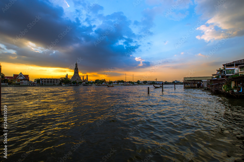 Fototapeta premium Wat Arun Ratchawararam Ratchawaramahawihan- Bangkok: Location at Chao Phraya River cruise tourists, dining on the boat and watch the evening light on the river, in Phranakhon, Thailand