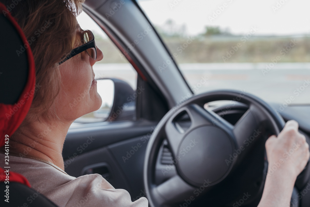 The elderly woman is driving the car The elderly woman is driving the car