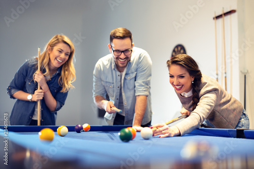 Tableau sur toile Three coworkers went to cafe after work to play some pool.