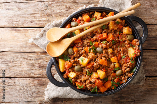 Delicious Picadillo cooked from ground beef with vegetables, raisins and spices close-up in a frying pan. horizontal top view