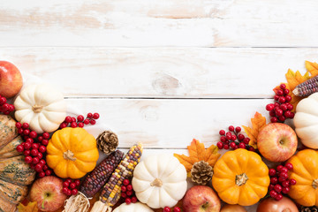 Top view of  Autumn maple leaves with Pumpkin and red berries on white wooden background. Thanksgiving day concept.