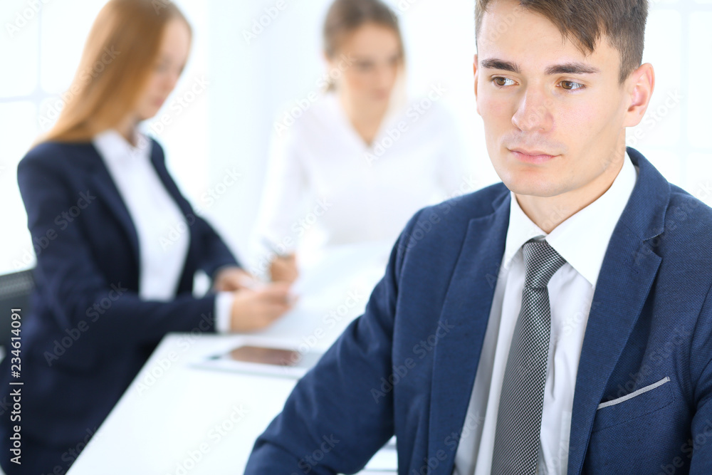 Group of business people or lawyers discussing terms of transaction in office. Focus at young businessman. Meeting and teamwork concept Group of business people or lawyers discussing terms of transaction in office. Focus at young businessman. Meeting and teamwork concept