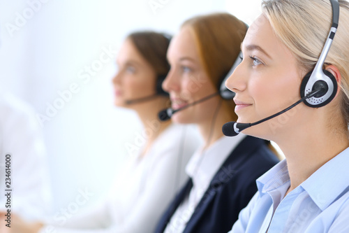 Call center. Group of operators at work. Focus at blonde business woman in headset