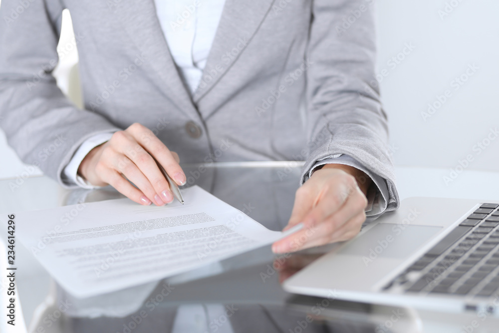 Fototapeta premium Close-up of female hands with pen over document, business concept. Lawyer or business woman at work in office