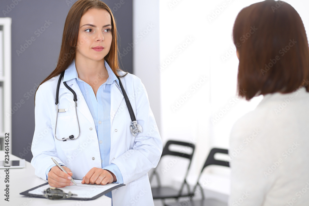 Doctor and patient discussing something while standing near reception desk in emergency hospital. Physician at work in clinic. Medicine and health care concept Doctor and patient discussing something while standing near reception desk in emergency hospital. Physician at work in clinic. Medicine and health care concept