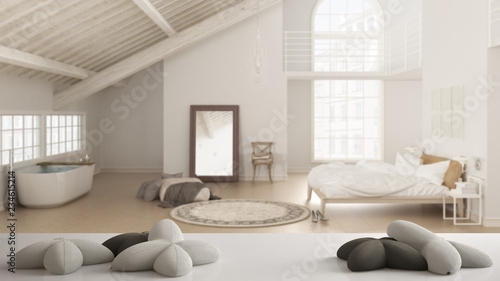 White table, desk or shelf with five soft white pillows in the shape of stars or flowers, over blurred loft with bedroom and bathroom, minimal architecture interior design concept