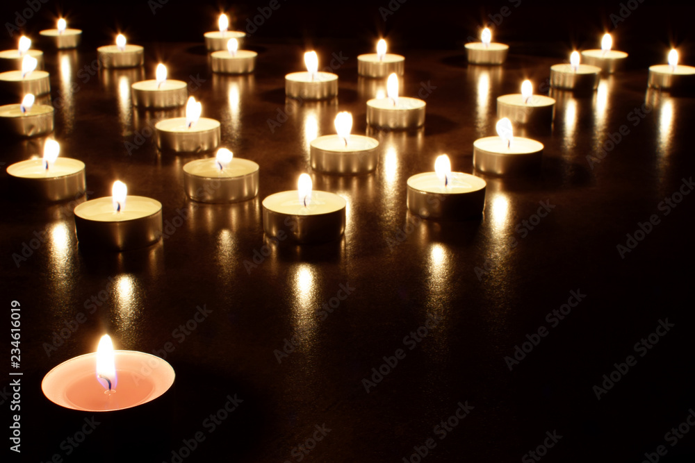 Tea light candles burning in darkness. Advent or memorial prayer candle flame.