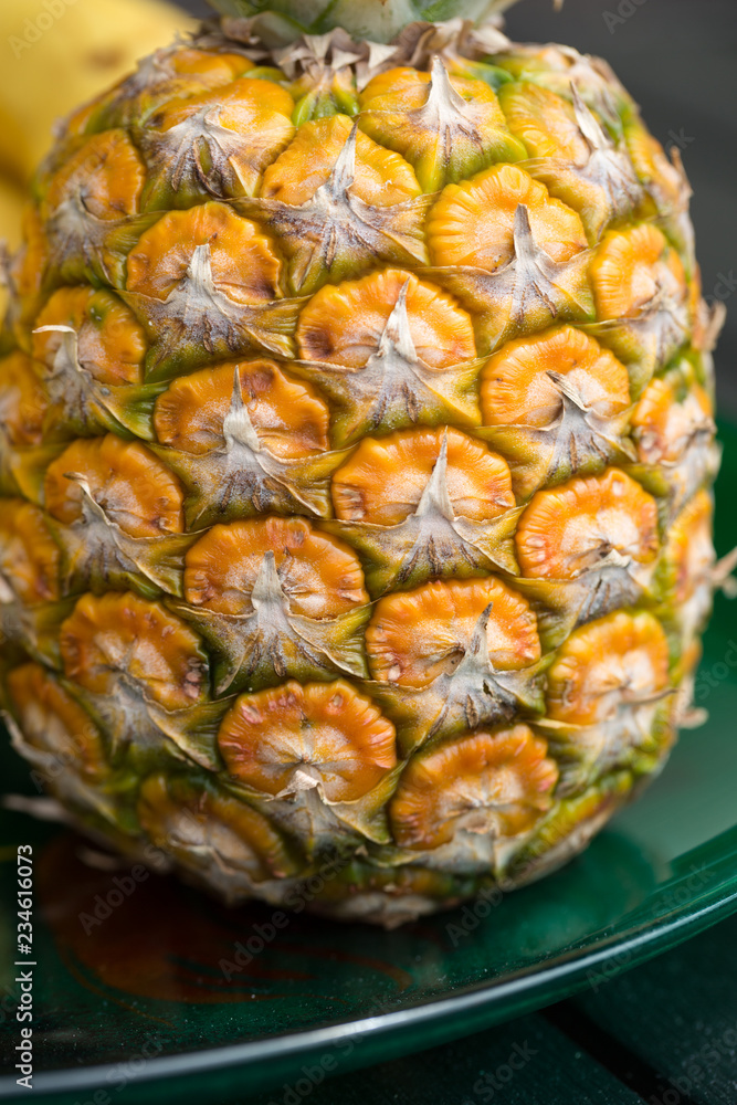 Ripe, fresh pineapple isolated on green plate