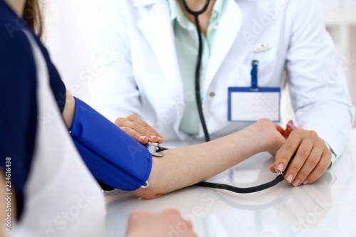 Doctor woman checking blood pressure of female patient, close-up. Cardiology in medicine  and health care concept photo