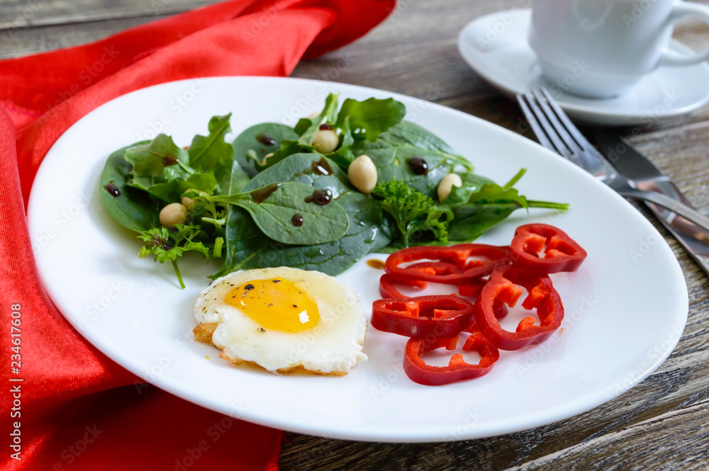 Light breakfast - quail egg, green salad, sweet pepper and a cup of tea on a wooden table. Healthy food. Proper nutrition.