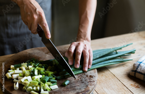 Cook chopping spring onions on a cutting board