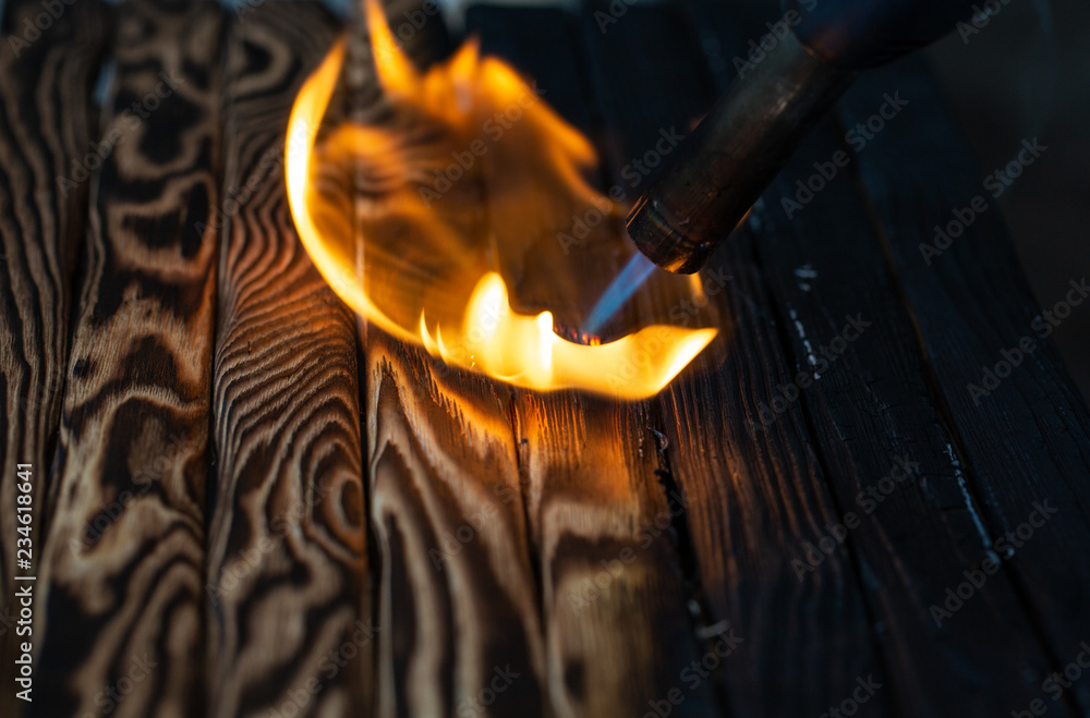 Fototapeta premium Charred wooden planks and fire. Background, texture. Flame. Wood processing.