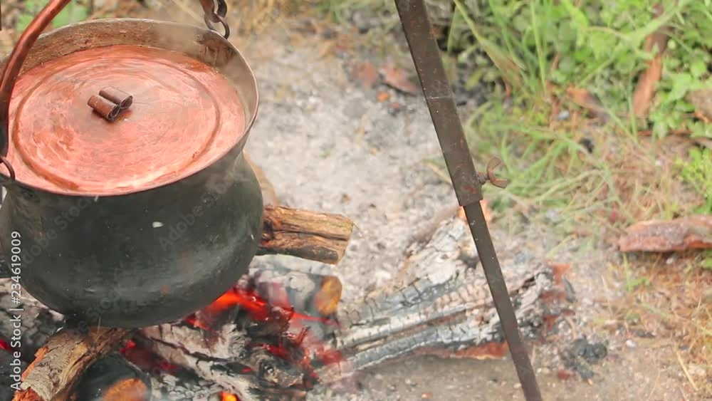 Cooking on fire in cast iron cauldron slider shoot. Cooking soup with meat and potatoes in cast iron cauldron Cooking on fire in cast iron cauldron slider shoot. Cooking soup with meat and potatoes in cast iron cauldron