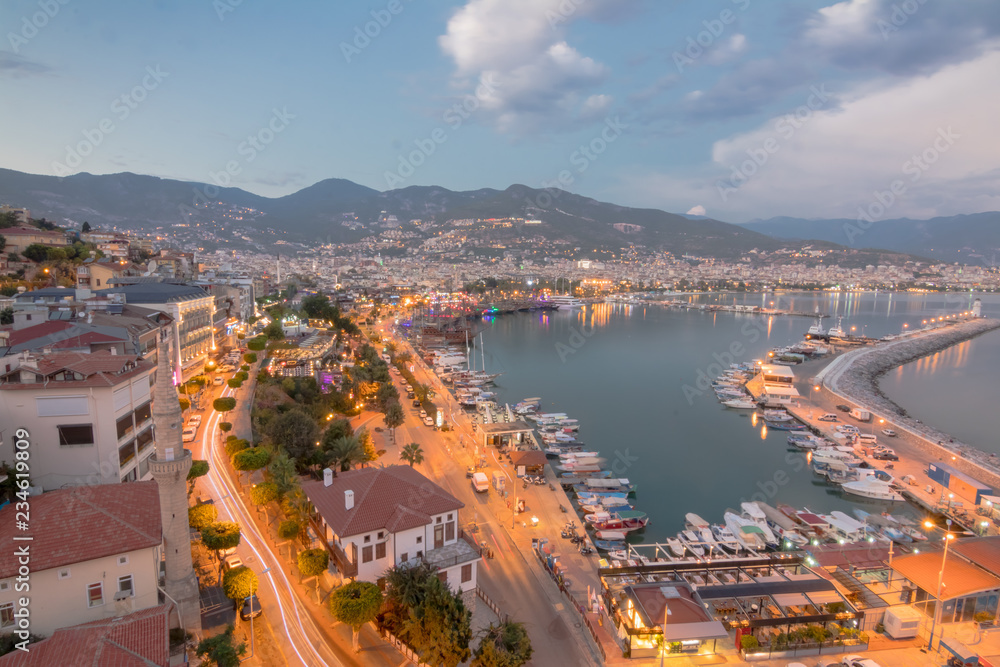 Alanya city harbor panorama in the evening with car traffic and ships and boats