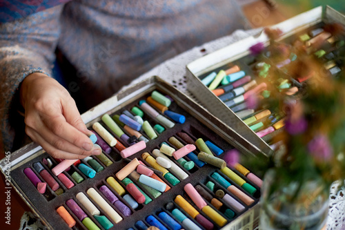 Box with pastel crayons and artist's hands. Drawing with dry pastel