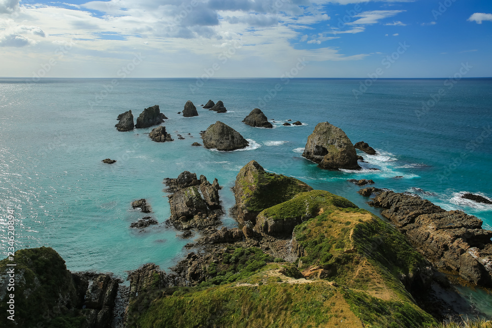 Nugget Point at Ahuriri Flat, New Zealand. Rocks scattered across the shore surrounded by the turquoise waters of the ocean.