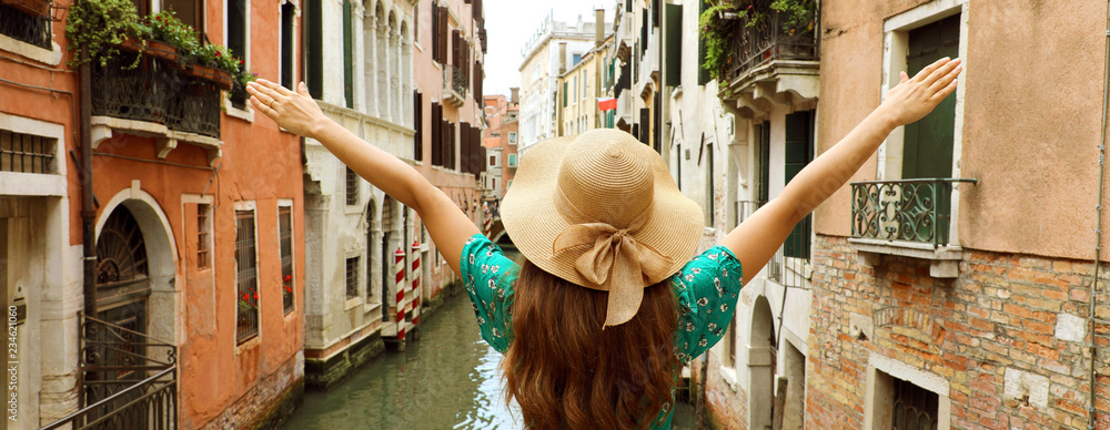 Fototapeta premium Europa podróży wakacje zabawy lato kobieta z rękami up i kapelusz szczęśliwy w Wenecja, Włochy. Panoramiczny widok transparent beztroski dziewczyna turystycznych w Europie przeznaczenia noszenia zielonej sukni mody.