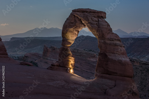  Red rock formation called Delicate Arch captured during night. A beam of light illuminates the part of the arch.